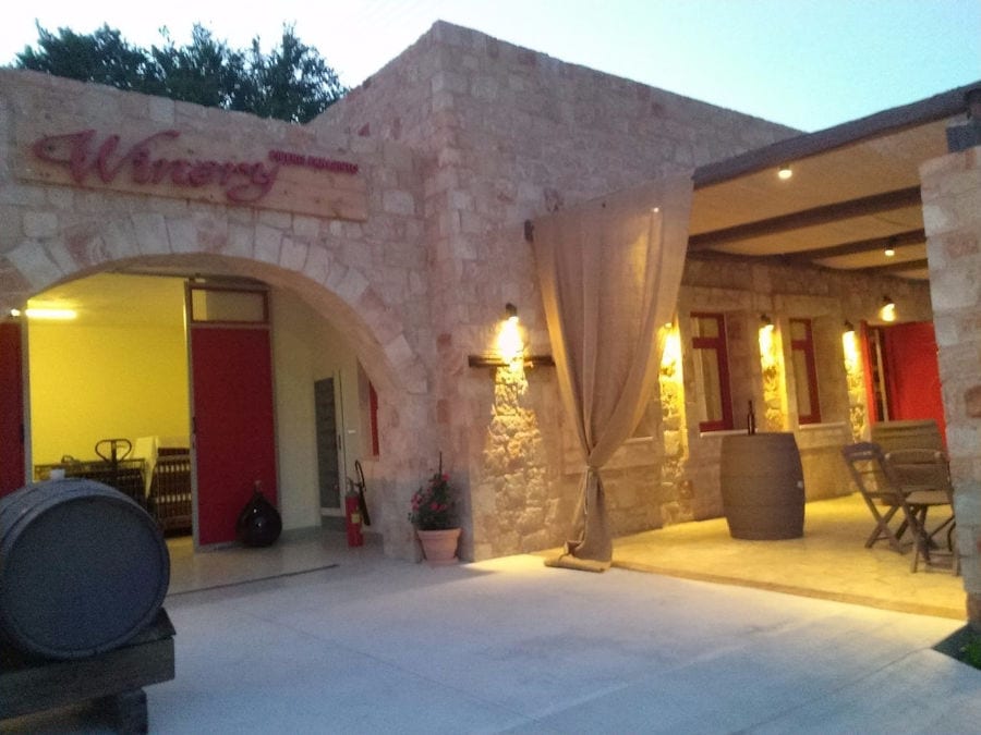 illuminated entrance of 'Piperis Winery' stone building by night